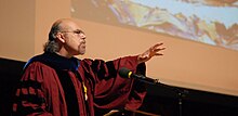 Carrasco delivers the Harvard Divinity School Convocation Address in front of an image of "Boxcar" by George Yepes.