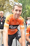 A male cyclist in partial uniform casually looking into the camera
