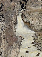 A powerful waterfall and rapids cut through jumbled rocks
