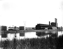 A factory on a river bend, viewed from across the river