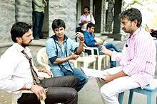 Sudeepa and Nani sit in chairs and listen to Rajamouli.