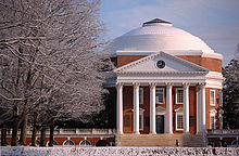 A red brick, Neoclassical dome with a large portico on the front and covered walkway on the sides. Snow covers the foreground and trees.