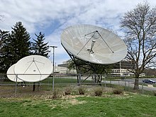 Two large, white satellite dishes mounted to the ground