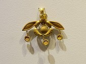 The Bee Pendant, an iconic Minoan jewel; 1700–1600 BC; gold; width: 4.6 centimetres (1.8 in); from Chrysolakkos (gold pit) complex at Malia; Archaeological Museum of Heraklion (Heraklion, Greece)[39][40]