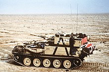 small armoured vehicle alone in the desert. The flag of the United Kingdom can just be seen on the rear
