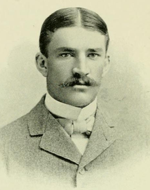 A man with a large mustache, wearing a suit with a bow tie, posing for a picture