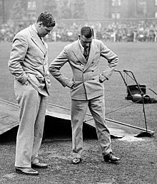 Two men inspect the ground on a wet cricket pitch