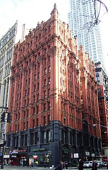 A lavishly-decorated red brick building seen at a 3/4 view