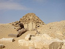 Crumbling pyramid in the desert with scattered stones in front
