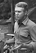 Black-and-white publicity photograph of a Caucasian man. The man has blonde hair and is wearing a shirt and a kerchief around the neck.