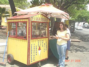 Customer posing with an older wooden piragua pushcart in Puerto Rico
