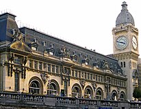 Fassade über der Eingangshalle mit Uhrturm, hinter den Bogenfenstern das Restaurant Le Train Bleu