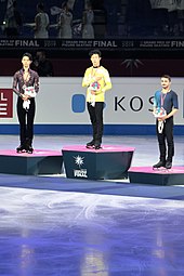 A photograph of Yuzuru Hanyu, Nathan Chen and Kevin Aymoz (from left to right) standing at the podium at a victory ceremony.
