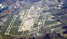An aerial view of an airport, with long stretches of runway scattered across a large green patch.