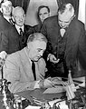 Very similar image showing Roosevelt signing the declaration of war against Germany, three days later.