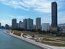 Aerial view of a seafront park, with skyscrapers forming the backdrop.