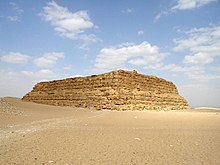 a large rectangular structure of yellow mudbricks in the desert