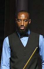 Rory McLeod is shown standing, holding a cue and looking down.