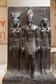 Statue of Menkaure with Hathor and Cynopolis; 2551–2523 BC; schist; height: 95.5 cm; Egyptian Museum (Cairo). Demonstrates a group statue with Old Kingdom features and proportions.[23]