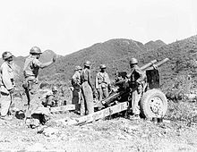 A group of men standing around a large gun
