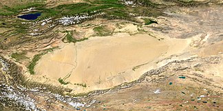Satellitenaufnahme des Tarimbeckens mit der Taklamakan-Wüste; im Südwesten Ausläufer des Himalaya. Das Tian-Shan-Gebirge befindet sich im oberen Bildteil nördlich des Tarimbeckens. In der linken oberen Bildecke der Yssyk-Köl-See. (NASA/MODIS/Blue Marble)