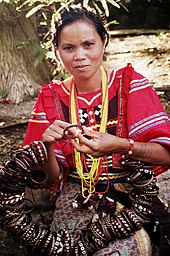 A Matigsalug woman in a red decorated tribal blouse making tribal bracelets