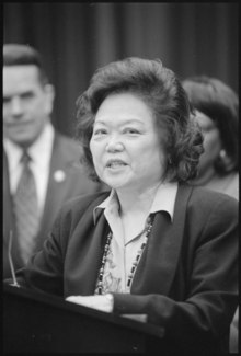 Black and white photograph of an Asian woman speaking at a podium