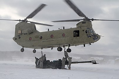 Soldiers of 1-119 FA sling-load an M777 155mm howitzer beneath a CH-47 Chinook at Camp Grayling Michigan on 1 March 2014.