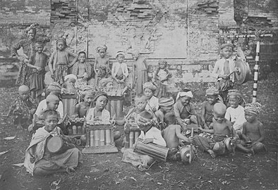 A gamelan ensemble consisting of children in a temple complex in Bali, between 1910 and 1920.