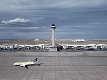 The Air Traffic Control Tower at Denver International Airport with a United Airlines Boeing 737-800 below.