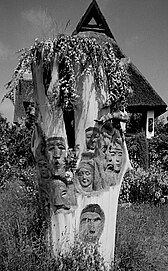 Ein Baumstumpf mit hinein geschnitzten Gesichtern von Hanns Mehner gestaltet