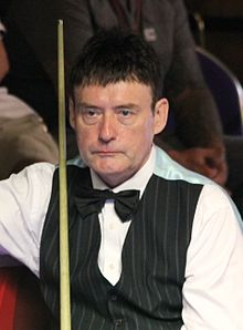 Jimmy White seated and holding his snooker cue.