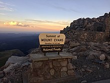 The United States Forest Service sign at the summit of Mount Blue Sky with the following inscription: ""Summit of Mount Evans Elevation 14,130 feet Arapaho & Roosevelt National Forests."