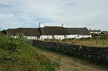 single story white thatched cottage