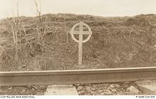 A black and white photograph of a white cross alongside a railway line