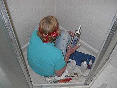 Repairing damaged tile in a shower stall with a caulking gun