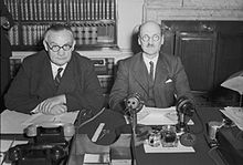 Two men sit side by side at a desk.