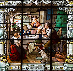 Stained glass depicting a family saying grace