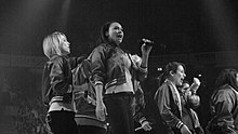 A group of female singers perform live on a stage.