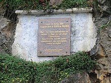 Memorial plaque reading the translated words "Monday July 12, 1971, tragedy in the Tour de France. On this road transformed into a torrent of mud by an apocalypse storm, Luis Ocaña, a yellow jersey, gave up all his hopes against this rock."