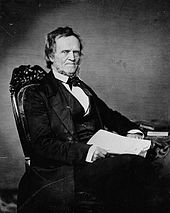 A portrait of William Lyon Mackenzie, depicted sitting in a chair with papers in his hands.