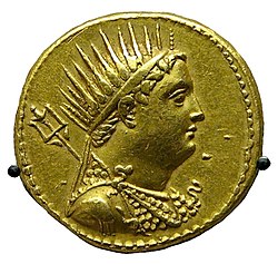 A gold coin shows the profiled bust of a man. The man is wearing a crown and drapery.