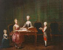 Four children around a table, a toddler in a blue dress on the left, a young teenager in pink seated and drawing, on her right a girl stands and helps her. A 6-year-old boy in a white-and-red military uniform is standing on the right with a book.