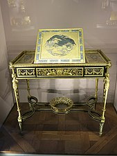 Writing table of Marie Antoinette; by Adam Weisweiler; 1784; oak, ebony and sycamore veneer, Japanese lacquer, steel, bronze gilt; 73.7 x 81. 2 cm; Louvre[69]