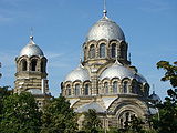 The church of the Theotokos Orans (Our Lady of the Sign) in Vilnius demonstrates typical features of developed Byzantine revival: exposed two-tone, striped, masonry; four symmetrical apses tightly fused into the main dome, creating a tall triangular outline; arcades blending into the domes; and a relatively small belltower, clearly subordinate to the main dome.