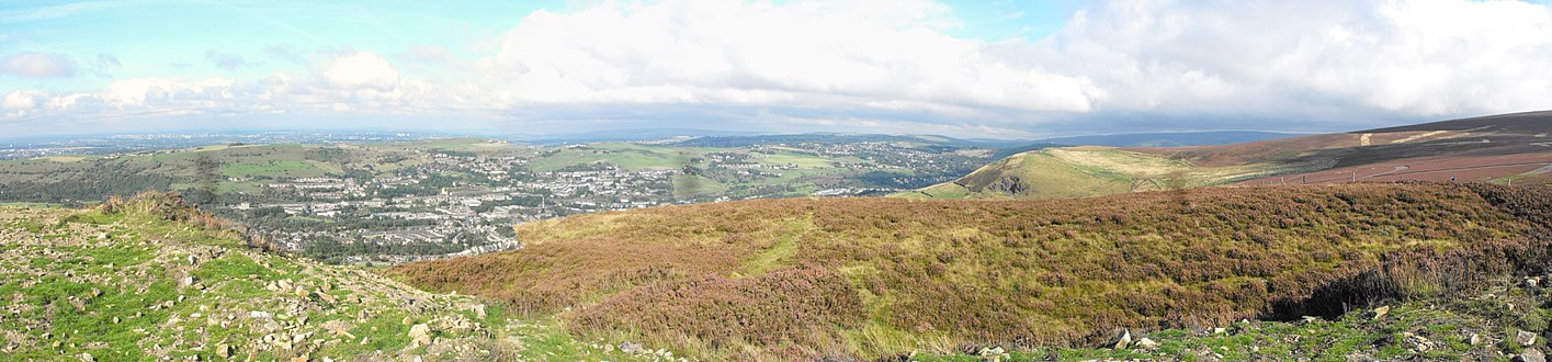 Heather-covered hillslopes in the foreground, with a plain in the background.
