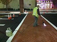 Polymer cement overlaying to change asphalt pavement to brick texture and color to create decorative crosswalk