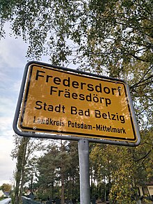 Zweisprachiges offizielles Ortseingangsschild von Fredersdorf, auf dem die niederdeutsche Ortsnamensvariante Fräesdörp unter dem hochdeutschen Namen steht