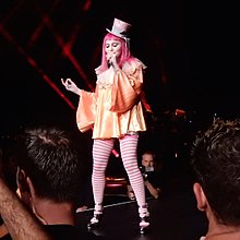 Madonna in a clown's dress and pink hair singing onstage