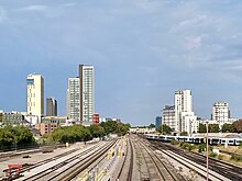multiple rail tracks leading away between tall buildings under a blue-grey sky